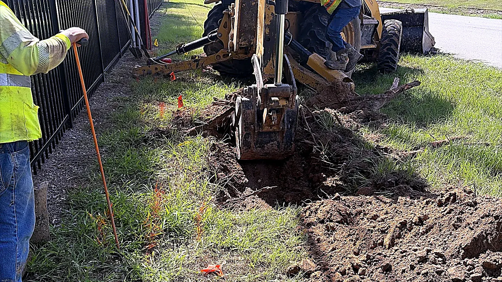 Backhoe trenching along a fence line