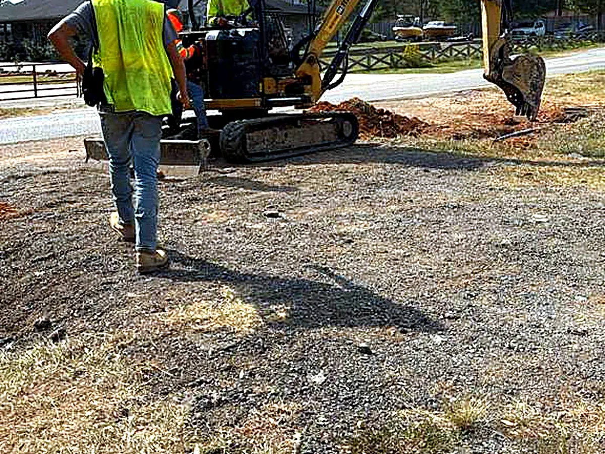 Spotter in high-visibility vest next to the excavator